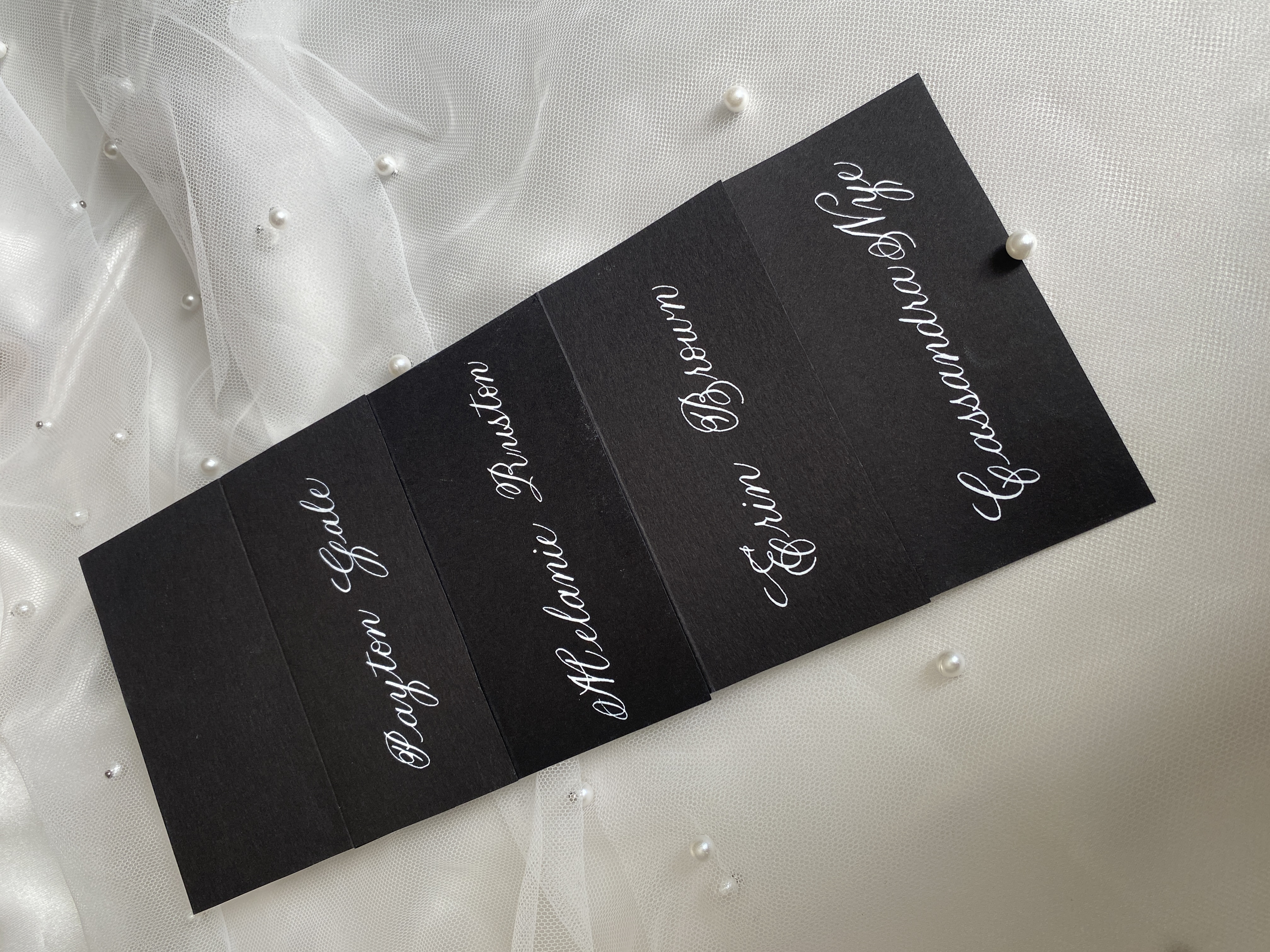 Black placecards on white satin fabric
